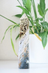 Wit, bruin en donkergroene Oceaan Jaspis toren van 21 cm met druzy kristallen, geplaatst op een minimalistische ondergrond.