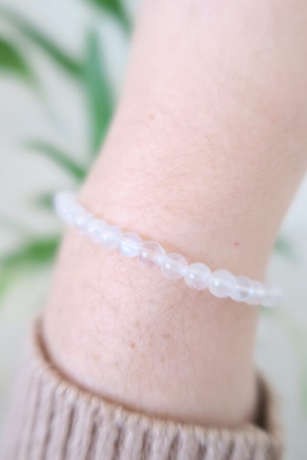 Witte maansteen armband met blauwe flash gedragen om een pols.