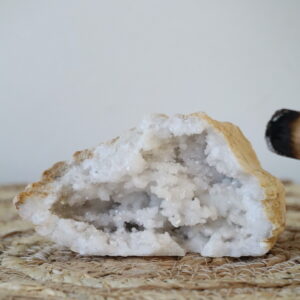 Marokkaanse kwarts geode van 297 gram op een natuurlijke ondergrond, met glinsterende kristalclusters.