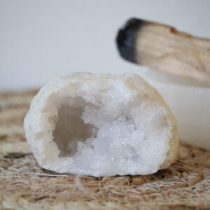 Marokkaanse Bergkristal Geode van 134 gram met fonkelende witte kristallen en een matte buitenkant, gefotografeerd op een natuurlijke ondergrond.