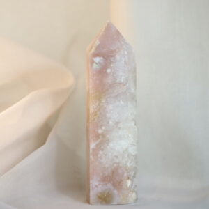 Roze Chalcedoon met Kwarts toren in zacht daglicht tegen een crèmekleurige achtergrond.