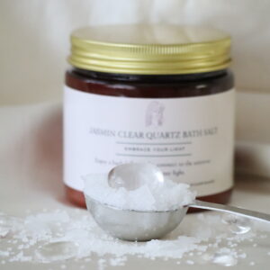 “Bergkristal Jasmijn badzout met Dode Zeezout, bergkristal steentjes en jasmijn, in amberkleurige pot met gouden deksel.”