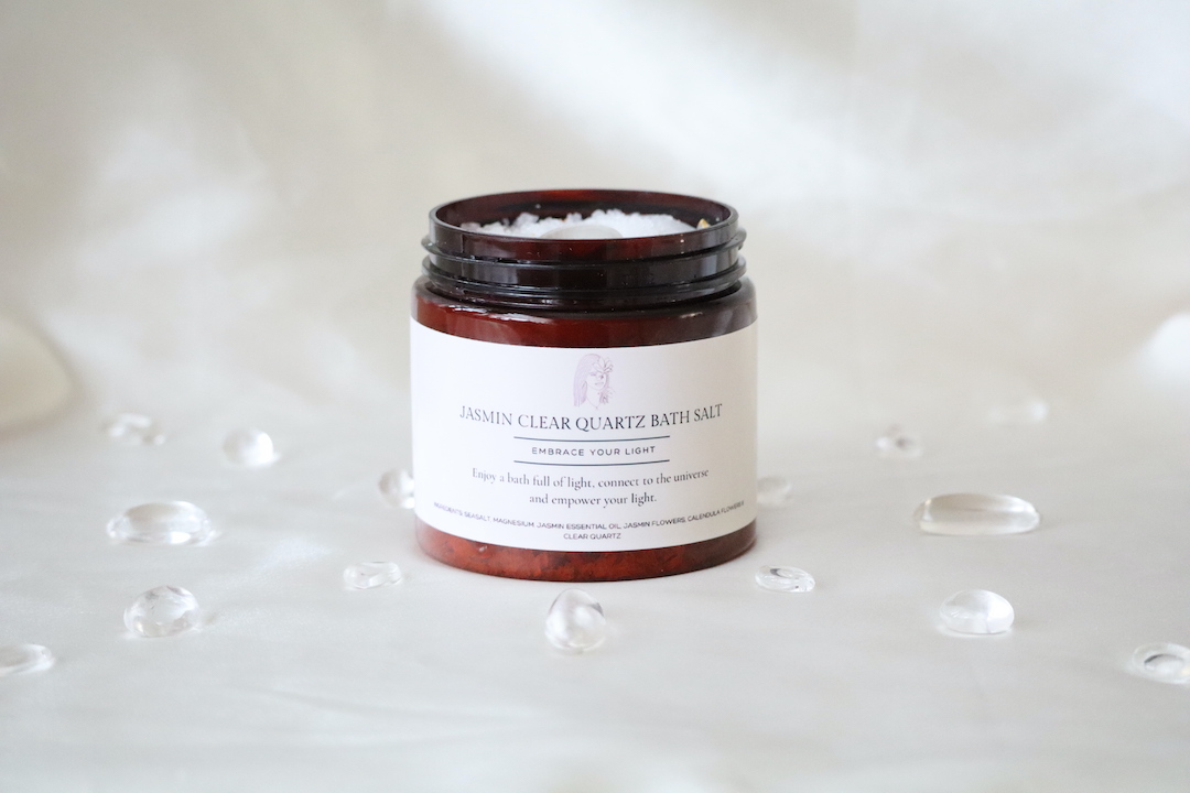 “Bergkristal Jasmijn badzout met Dode Zeezout, bergkristal steentjes en jasmijn, in amberkleurige pot met gouden deksel.”