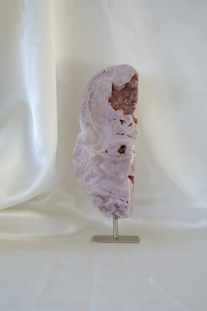Bubbel druzy roze chalcedoon op metalen standaard met zachte poederroze tinten, open kristalholtes en ronde bubbelstructuren, gefotografeerd in natuurlijk daglicht.
