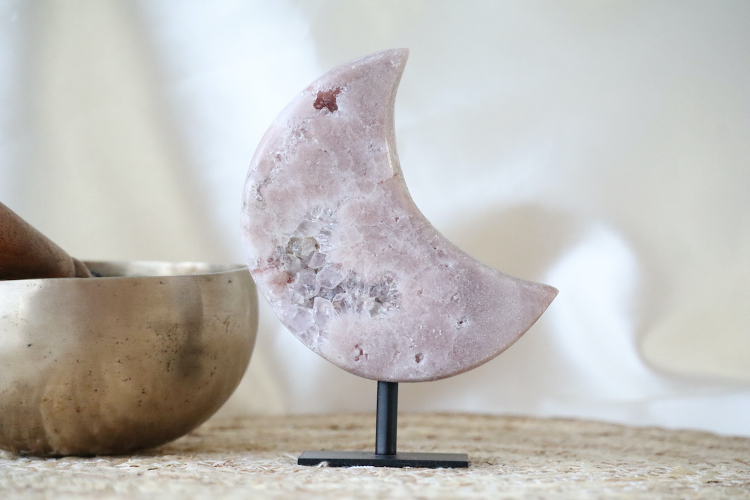 Roze chalcedoon met kwarts maan op zwarte metalen standaard, gepolijste maanvorm met zachte poederroze tinten en subtiele kristalstructuur, gefotografeerd in natuurlijk daglicht.