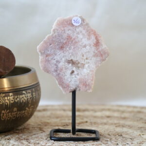 Roze chalcedoon met kwarts op zwarte metalen standaard, zachte poederroze tinten en heldere kristalstructuren, gefotografeerd in natuurlijk daglicht tegen een rustige interieurachtergrond.