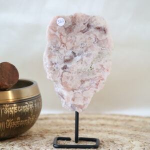 Roze chalcedoon met kwarts op zwarte metalen standaard, zachte poederroze tinten met natuurlijke adering en lichte kristallijne structuren, gefotografeerd in natuurlijk daglicht.