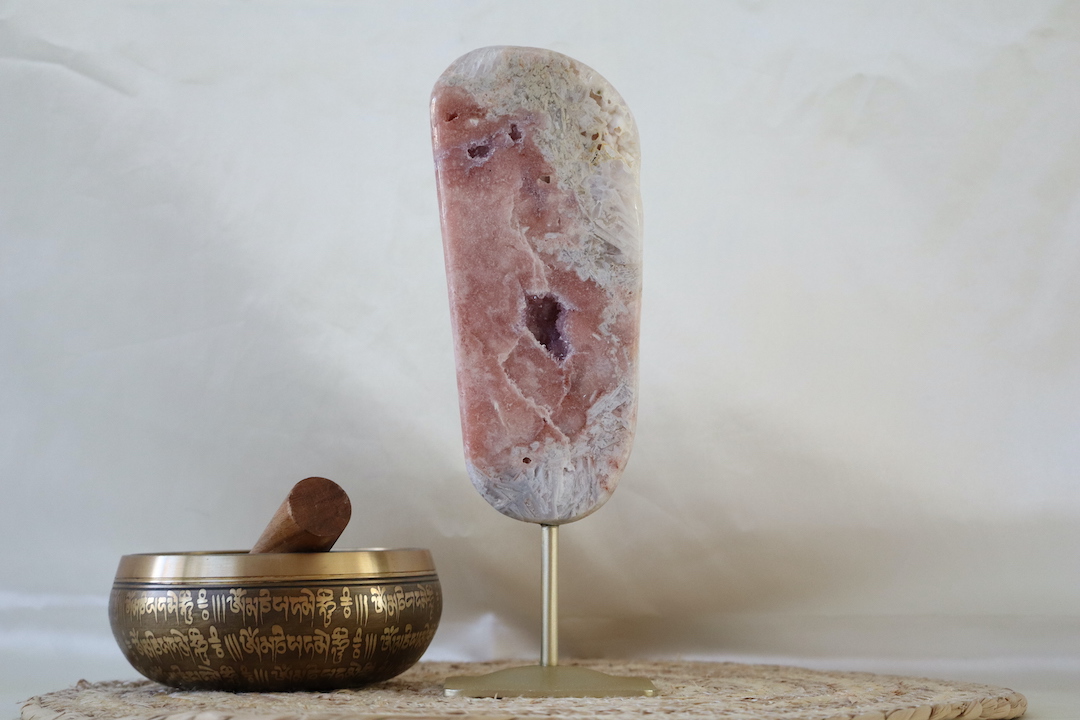 Roze chalcedoon met amethist en rutielkwarts op metalen standaard, langgerekt natuurstuk met zachte roze tinten en kristallijne structuren, gefotografeerd in natuurlijk daglicht.