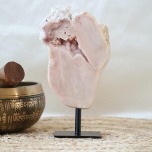 Druzy roze chalcedoon op zwarte metalen standaard met open kristalholte en bubbelachtige formaties, zachte poederroze tinten, gefotografeerd in natuurlijk daglicht.