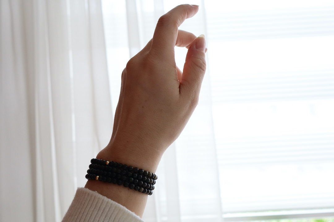 Goud obsidiaan armband 4 mm gedragen om de pols met subtiele gouden reflectie.