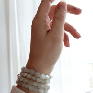 Groene Maansteen trommelsteen armband 6-8mm gedragen om de pols met zachte groenwitte kralen.