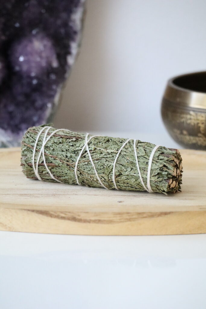Organische Ceder Smudge Stick van 10 cm op een houten schaal.