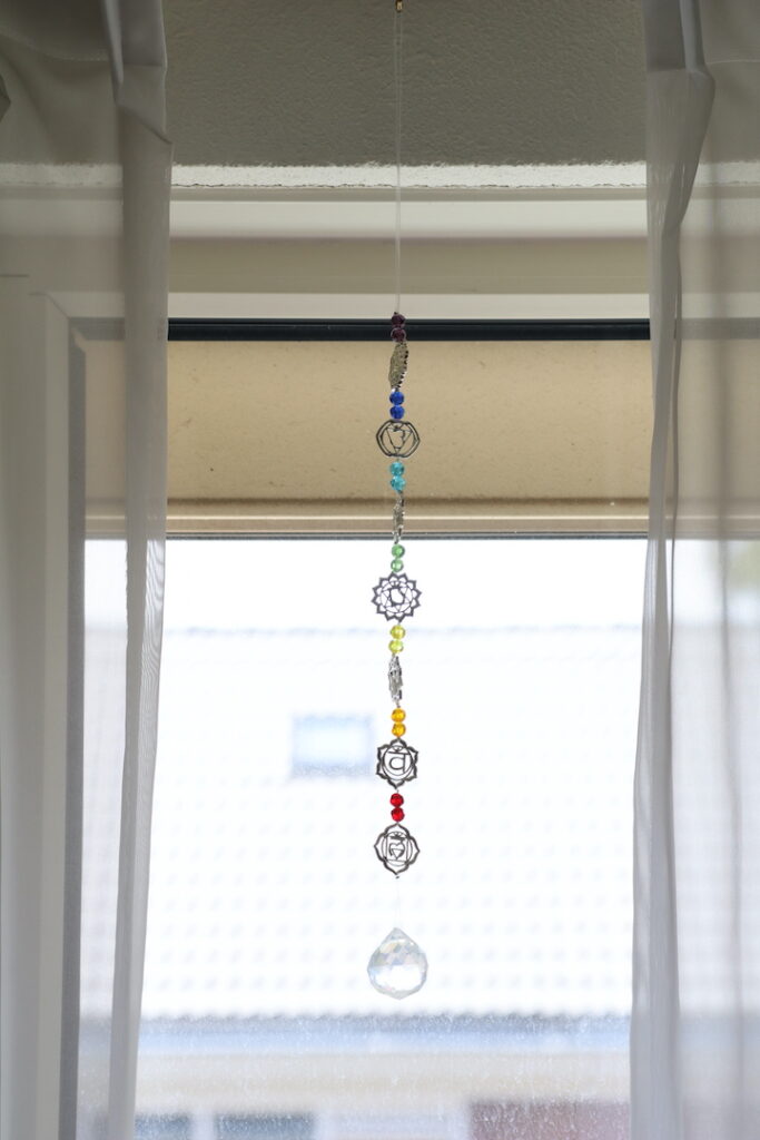 Detailfoto van de Chakra Zonnevanger met kleurrijke chakra kralen en heldere kristalhanger.