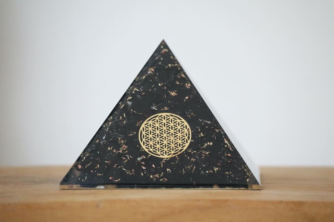 Shungiet Orgoniet Piramide met Flower of Life op houten ondergrond.