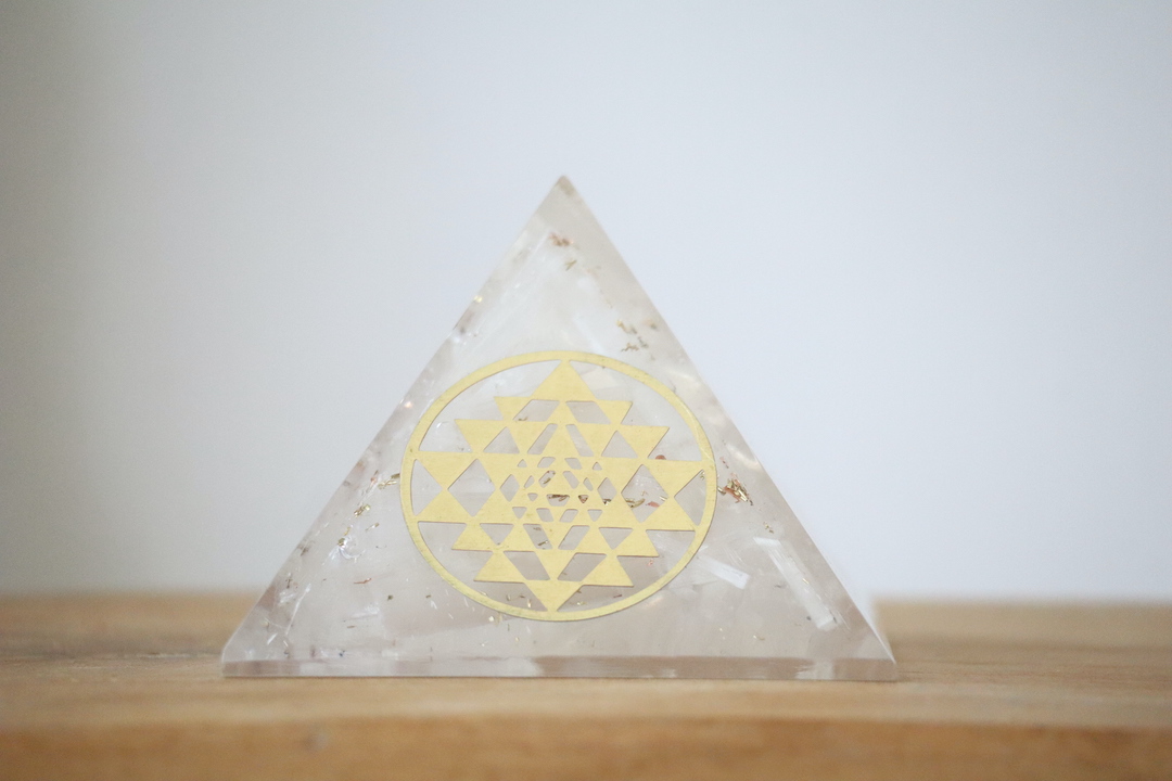 Seleniet Orgoniet Piramide met Sri Yantra op een houten ondergrond.