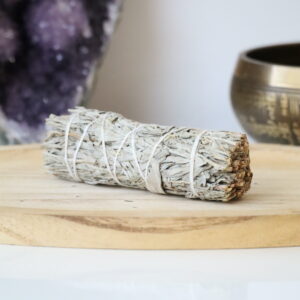 Witte & Blauwe Salie Smudge Stick van 10 cm op een houten schaal.