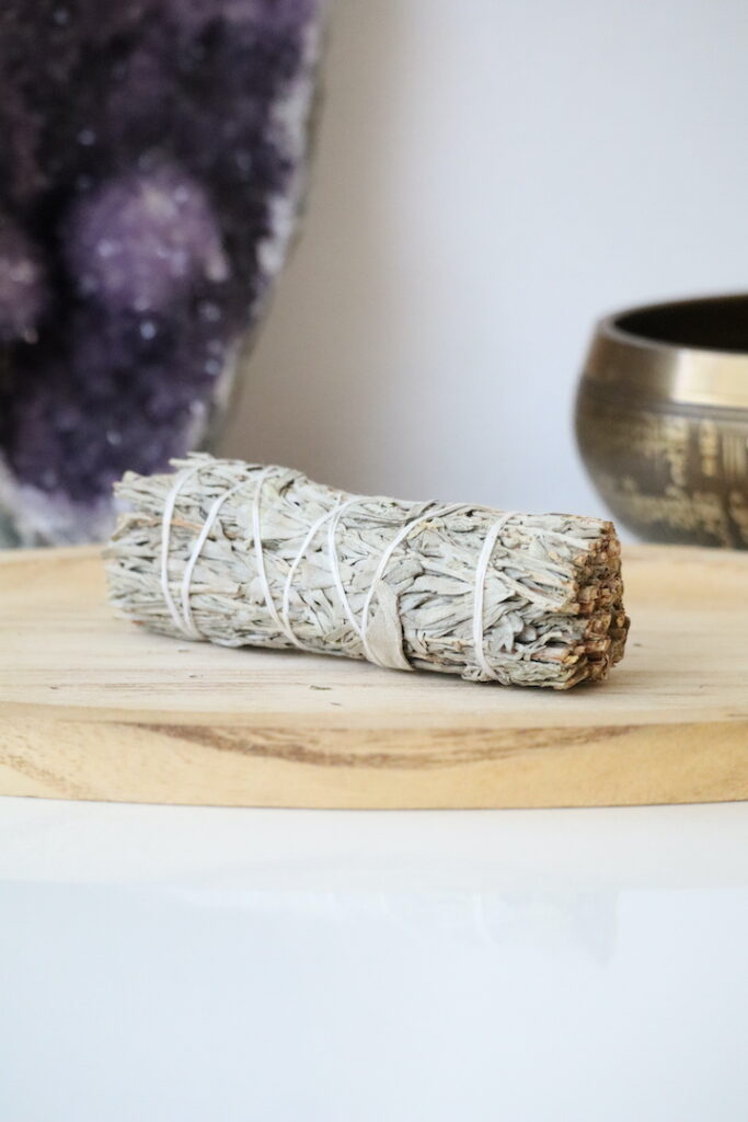 Witte & Blauwe Salie Smudge Stick van 10 cm op een houten schaal.