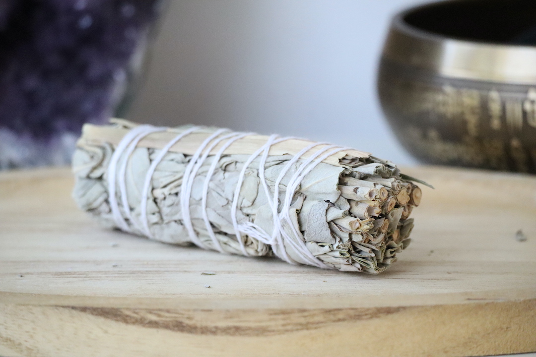 Organische Witte Salie & Citroengras Smudge Stick op een houten schaal.