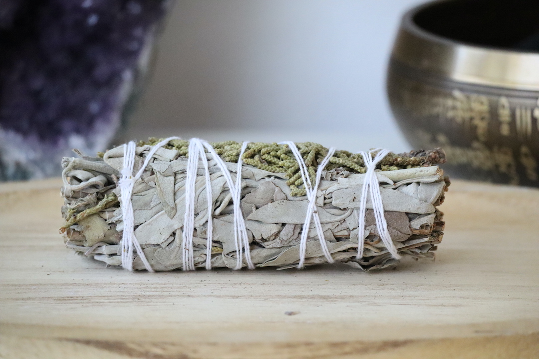Witte Salie & Jeneverbes Smudge Stick van dichtbij op een houten ondergrond.