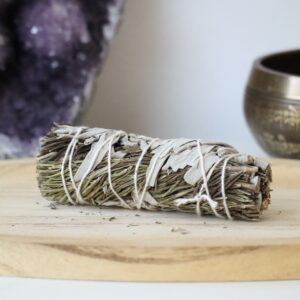 Witte Salie & Rozemarijn Smudge Stick van 10 cm op een houten schaal.