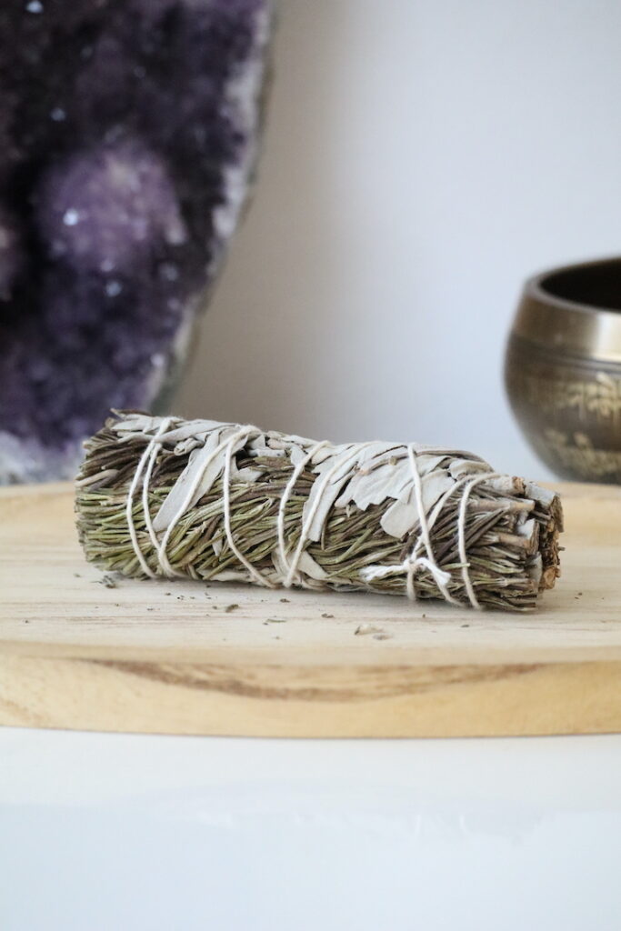 Witte Salie & Rozemarijn Smudge Stick van 10 cm op een houten schaal.
