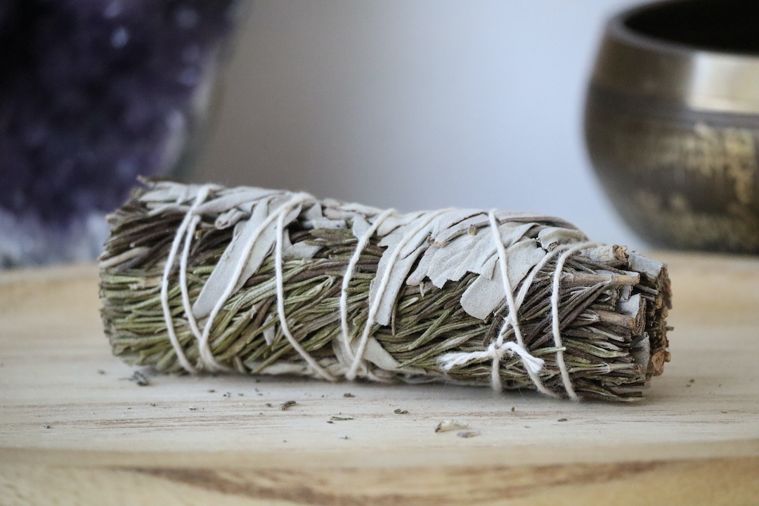 Witte Salie & Rozemarijn Smudge Stick van dichtbij op een houten ondergrond.
