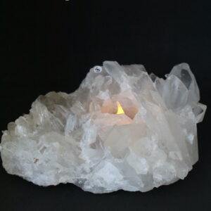 Bergkristal cluster waxinehouder met warm LED-licht tussen grote doorschijnende kristalpunten.