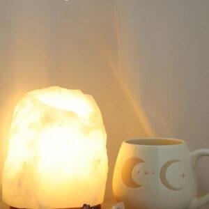 Witte zoutlamp van 2-3 kg met warme honingkleurige lichtgloed, keramieken maanfasen mok en edelstenen.