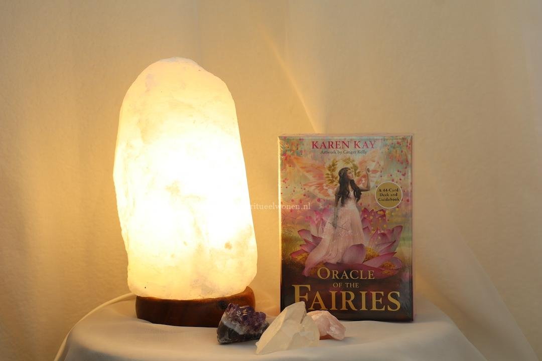 Verlichte witte zoutlamp naast Oracle of the Fairies orakelkaarten, amethist, bergkristal en rozenkwarts.